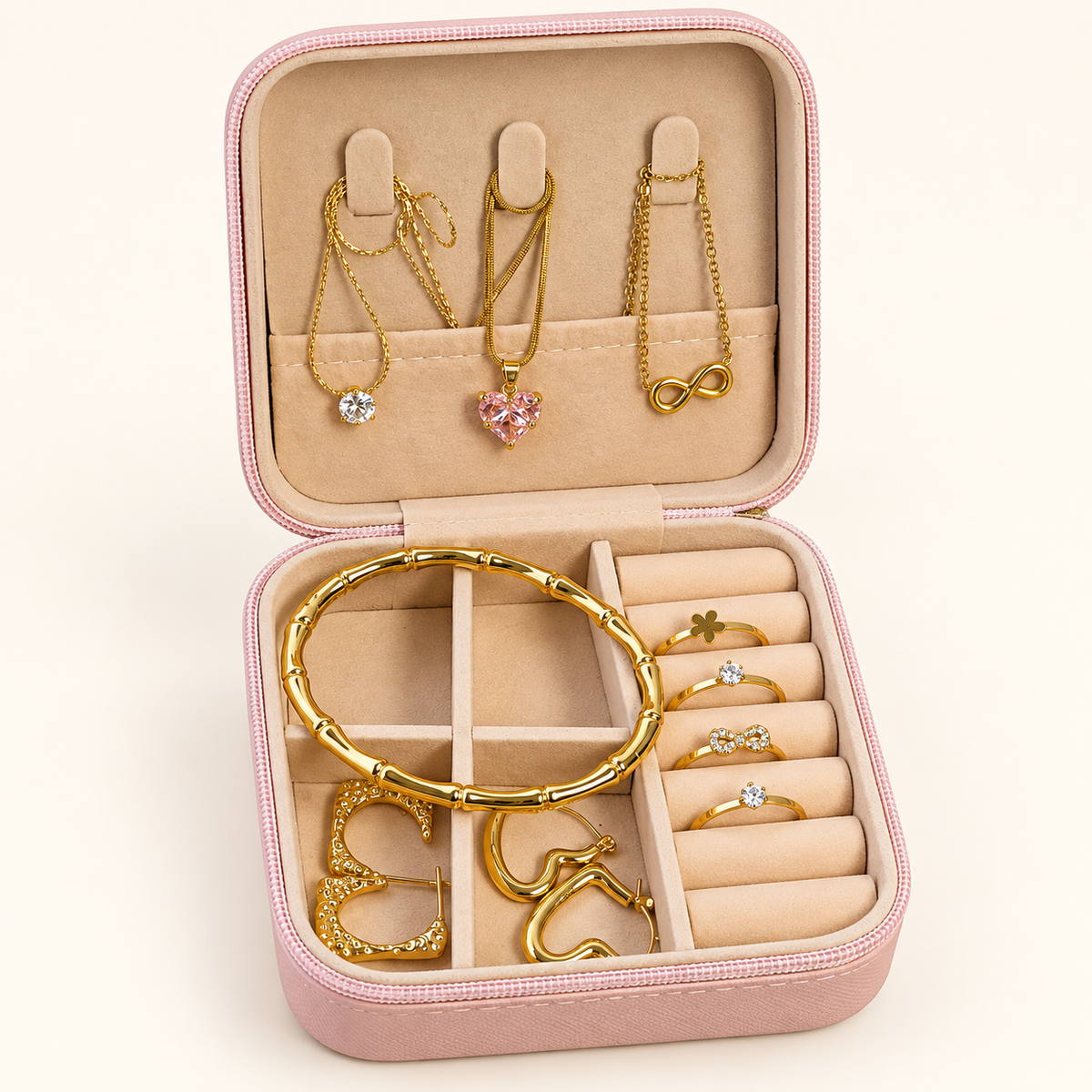 Open pink jewellery box with crystal, pink heart and infinity necklaces, gold-tone bangle, earrings and rings