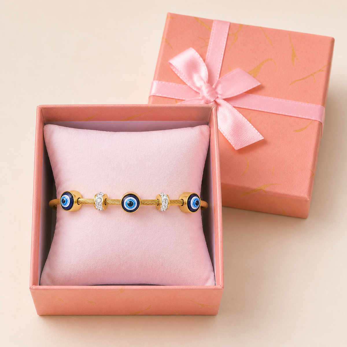 Anti-Tarnish Evil Eye kada in an open blush-pink gift box — worn around the cushion