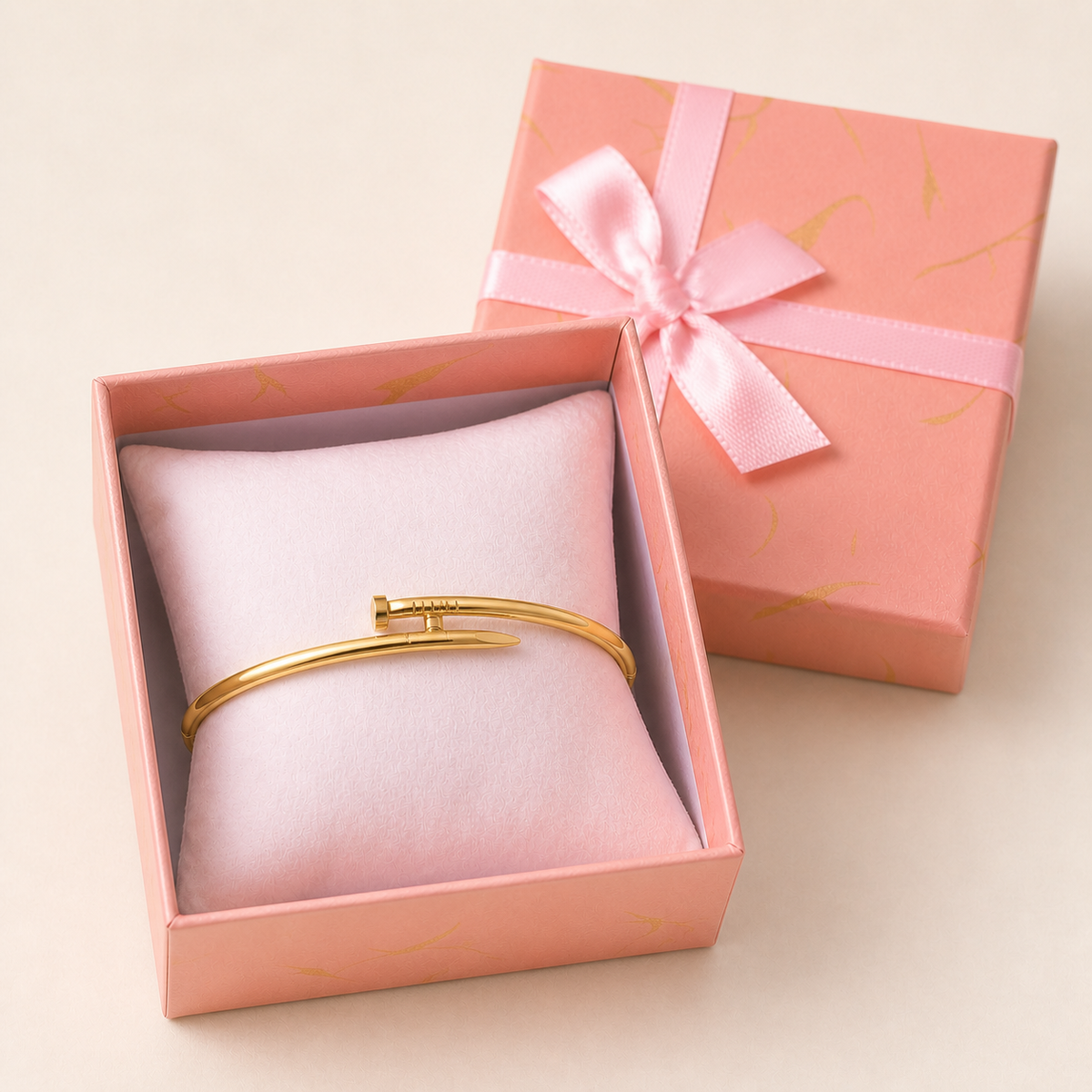 Gold-Toned Bracelets in an open blush-pink gift box — worn around the cushion
